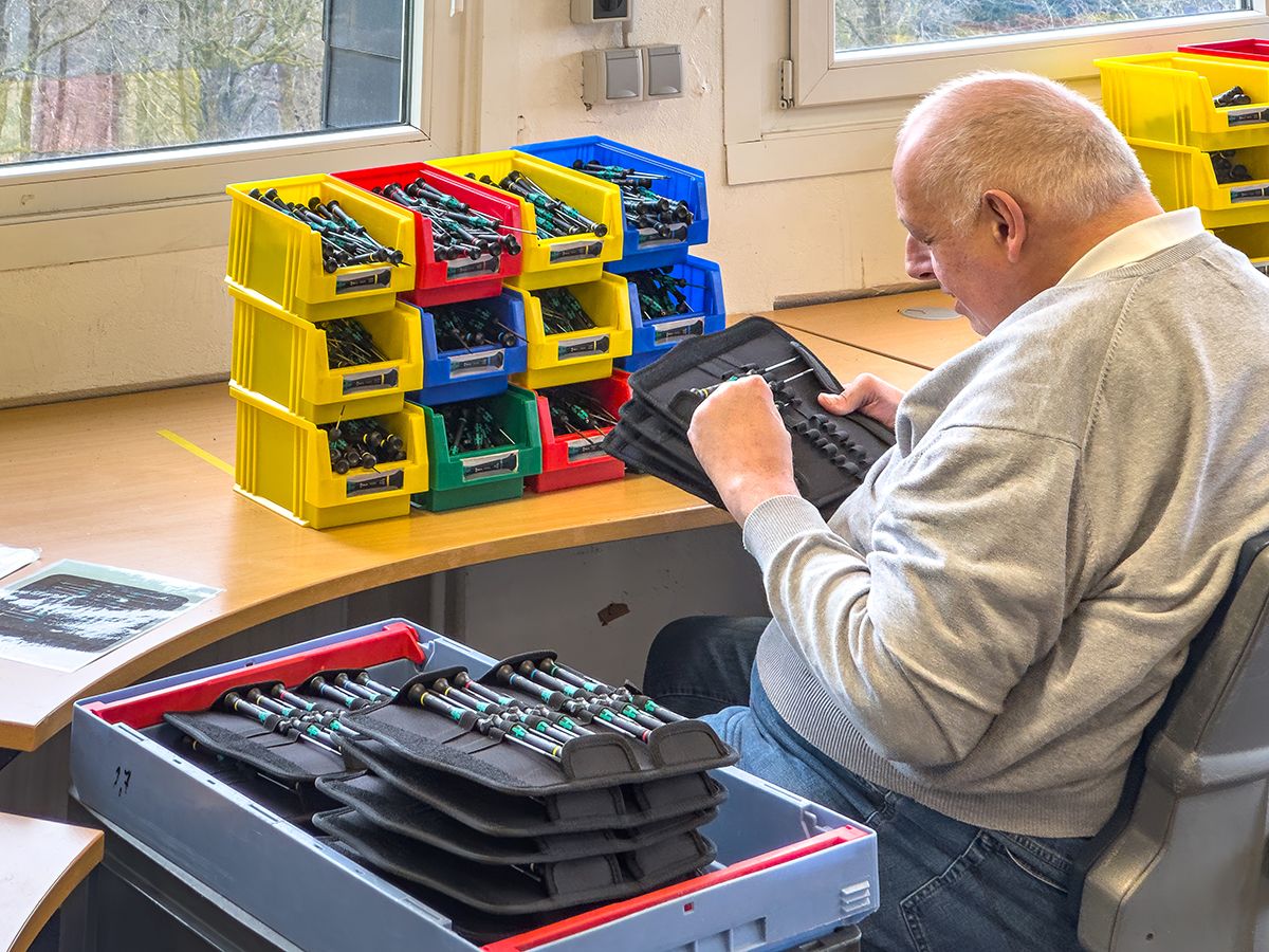 Ein Mann arbeitet in einer Werkstatt und sortiert Produkte.